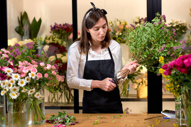 Photo of successful modern florist wearing apron making creating bouquet of flowers - Zdjęcie, obraz