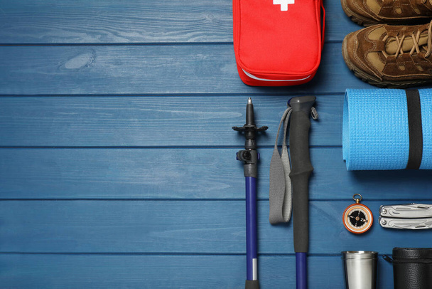 Flat lay composition with trekking poles and other hiking equipment on blue wooden background, space for text - Valokuva, kuva