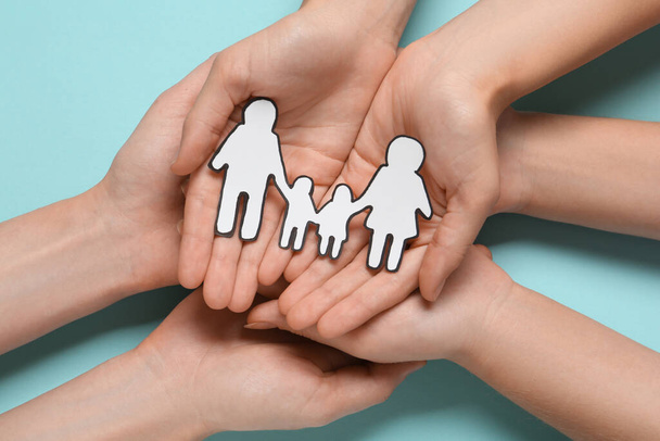 People holding paper family cutout on light blue background, top view - Fotoğraf, Görsel
