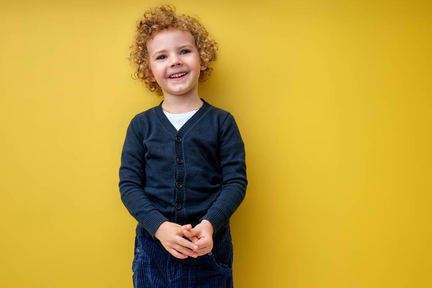 Adorable boy posing at camera isolated over yellow background in studio - Φωτογραφία, εικόνα