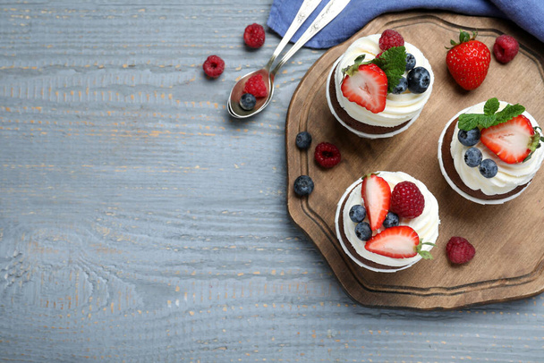 Sweet cupcakes with fresh berries on wooden table, flat lay. Space for text - Фото, зображення