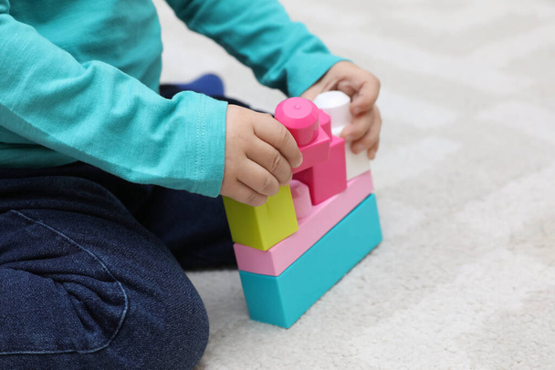 Little child playing with building blocks on carpet, closeup - Fotoğraf, Görsel