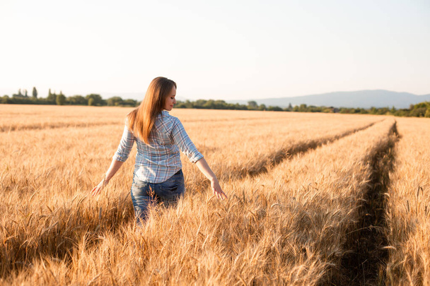 Charming woman enjoying moment, walking in grain field - Valokuva, kuva