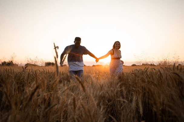 Young adult couple holding hands while walking in field - Foto, Imagem