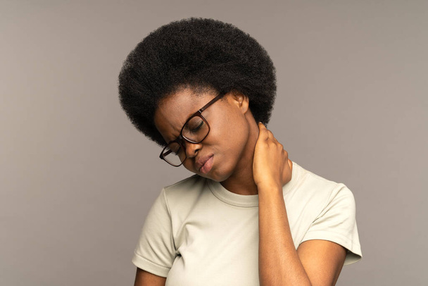 Femme millénaire noire bouleversée massage cou souffrant de maux de dos ou de spasmes musculaires pour soulager la douleur - Photo, image