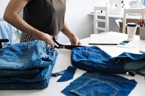 Denim Upcycling Ideeën, Het gebruik van Oude Jeans, Repurposing Jeans, Hergebruik van Oude Jeans, Upcycle Stuff. Vrouwelijke naaister knippen en repareren oude blauwe jeans in naaiatelier. - Foto, afbeelding