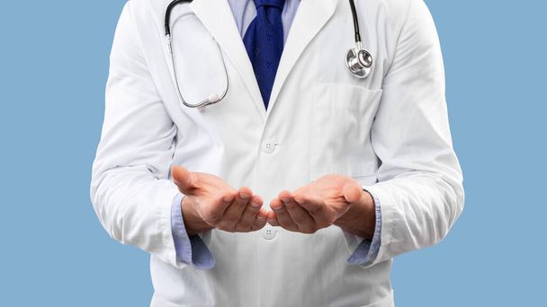 Unerkannter Arzt zeigt unsichtbares Objekt vor blauem Hintergrund, Panorama - Foto, Bild