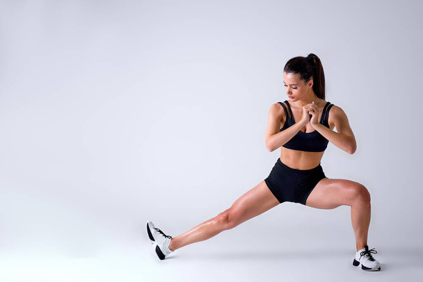 Healthy Caucasian Fit Female In Sportswear Doing Lunges In Studio On White Background - 写真・画像