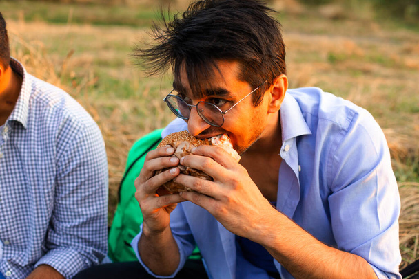 Yetişkin öğrenci dışarıda hamburger yiyor. - Fotoğraf, Görsel