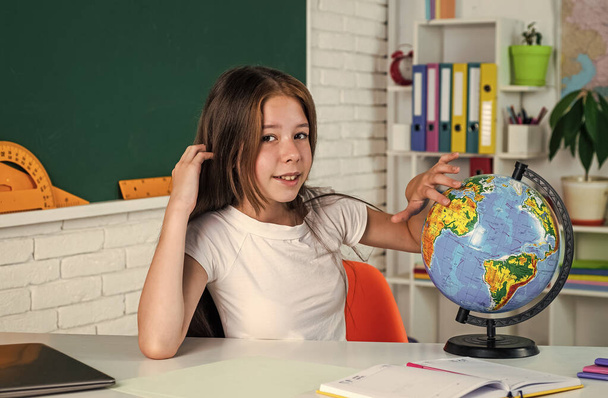 child look at globe. geography. back to school. formal education in modern life. home schooling concept. childhood development. get knowledge through study. kid in classroom with chalkboard - Valokuva, kuva