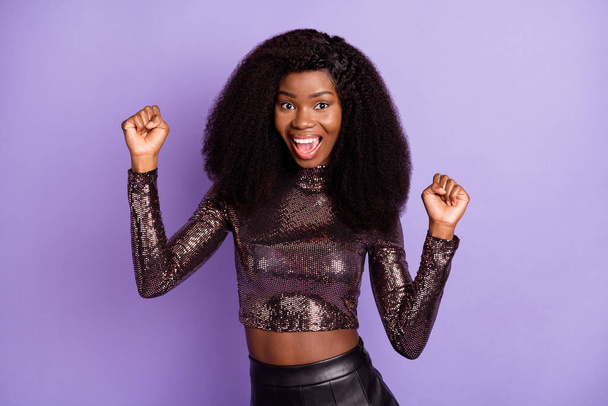 Photo of young attractive happy cheerful excited african girl hold fists in victory isolated on violet color background - Фото, изображение