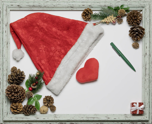 Composition sur le thème de Noël avec un chapeau de Père Noël, un cœur dans un cadre et un endroit propre pour une inscription. Une maquette de Noël. Vue du dessus - Photo, image