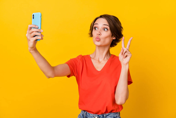 Photo of nice brunette optimistic lady do selfie blow kiss show v-sign wear red t-shirt isolated on vivid yellow color background - Foto, Imagem