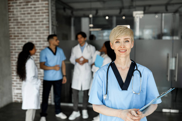 Mulher loira atraente médico assistindo conferência médica, sorrindo para a câmera - Foto, Imagem