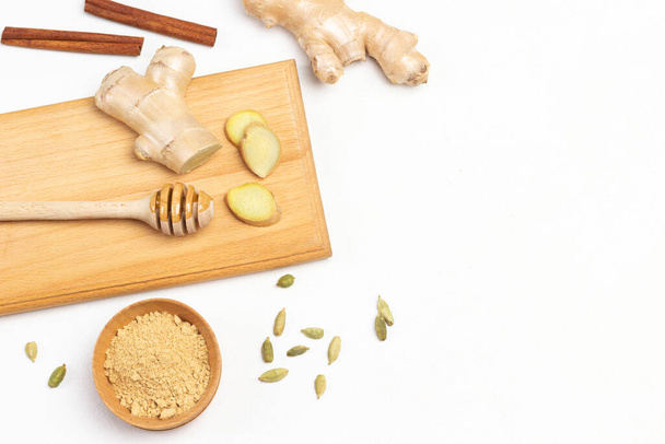 Stick with honey, ginger root on board. Cardamom and dry ginger on table. Copy space. Flat lay. White background. - Fotoğraf, Görsel