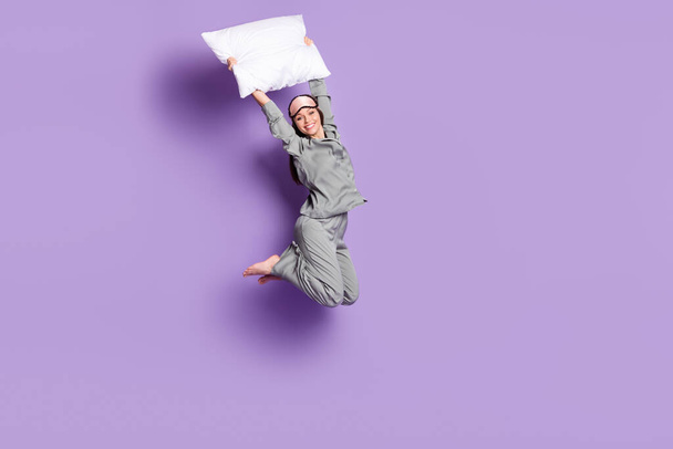 Full length body size photo of girl jumping keeping white pillow in bedroom isolated pastel violet color background - Foto, Imagem
