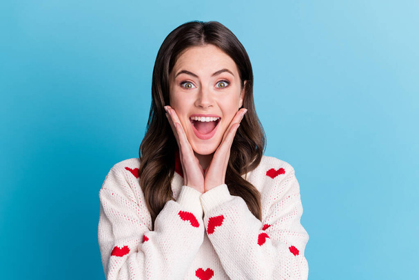 Photo of adorable excited young woman dressed hearts print pullover arms cheeks isolated blue color background - Foto, imagen