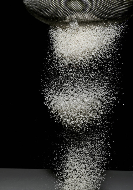 Preparing food by sifting flour on a black backgroung - Фото, изображение