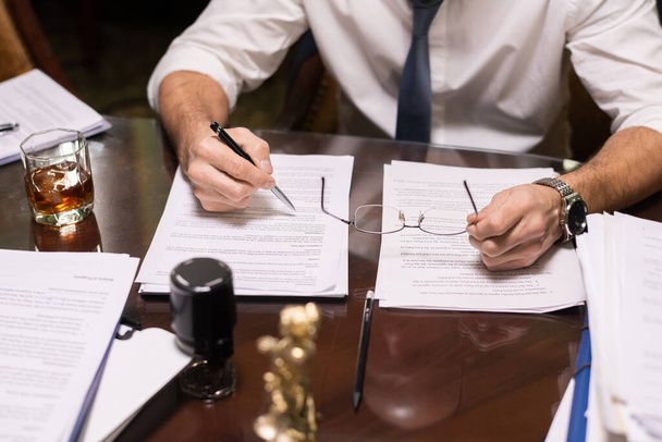 Зрілий бізнесмен тримає ручку над документом, читаючи його
 - Фото, зображення