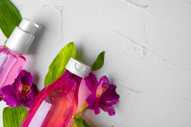 Bottle of fragrance or aromatic oil in a bunch of fresh flowers - Foto, imagen