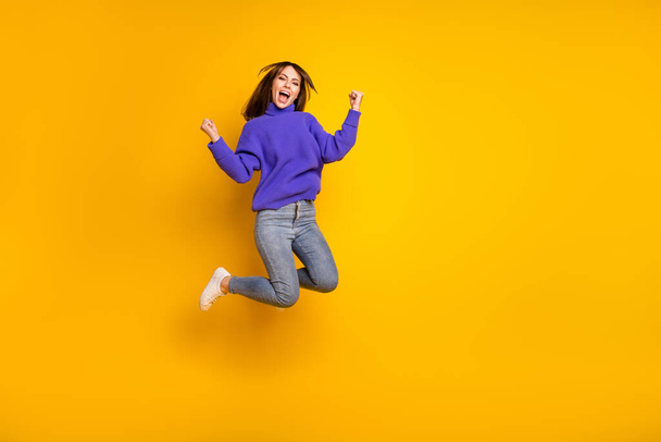 Full length body size view of attractive cheerful lucky girl jumping having fun rejoicing isolated over bright yellow color background - Zdjęcie, obraz