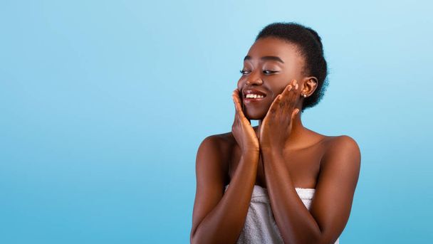 Концепция подтяжки лица. Счастливая африканская американка касаясь мягкой гладкой кожи на щеках на голубом фоне, панорама - Фото, изображение