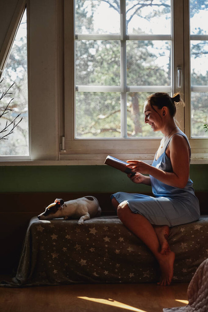 Beautiful brunette woman reading a book by the window  - Φωτογραφία, εικόνα