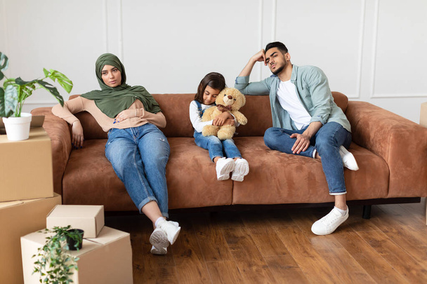Уставшая семья сидит на диване с картонными коробками - Фото, изображение
