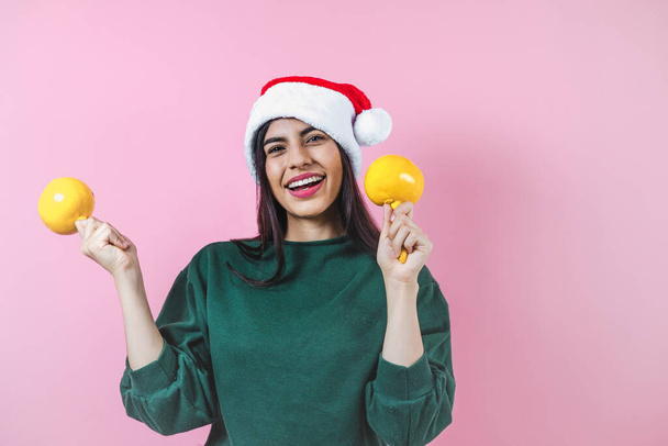 Portrait of young latin woman holding maracas rattle with copy space in a christmas concept on pink background - Photo, Image