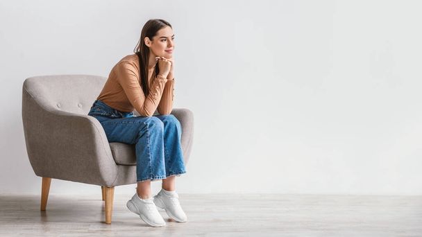Dreamy millennial woman looking at blank space with pensive facial expression against white studio wall, panorama - Photo, Image