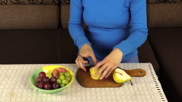 broušené hruška na talíř na stůl s ubrusem a ovoce váza - Záběry, video