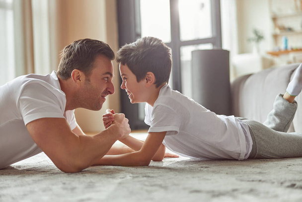 Lustiger Vater und Sohn beim Armwrestling zu Hause - Foto, Bild