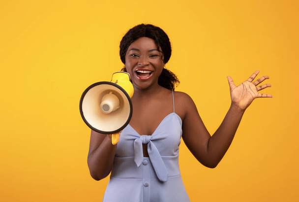 Gran oferta de compras. Milenial mujer negra gritando en megáfono, anunciando gran venta en fondo de estudio naranja - Foto, imagen