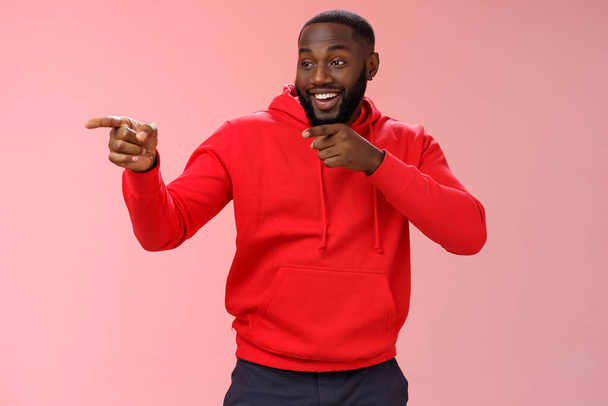 Hey mate what up. Portrait cheeky confident outgoing african american bearded man entering club see friends make hello gesture pointing left finger pistols sassy smiling, standing pink background - Photo, Image