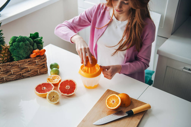 Red hair woman making citrus fruits juice for healthy lifestyle design. Healthy diet. Fruit juice. - Photo, Image