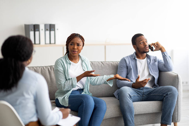 Раздраженная афроамериканка жалуется на чрезмерное использование смартфонов мужьями во время психологической консультации - Фото, изображение