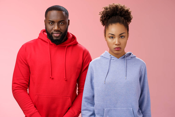 Two cute african american siblings standing together pink background invited family dinner greet new mom boyfriend, sister look displeased serious brother smug have idea prank stepdad - Photo, Image