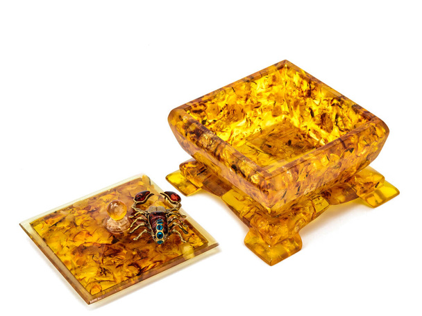 Escorpión de bronce en joyero ámbar abierto para almacenar artículos pequeños y accesorios, decoración interior. Cofre amarillo naranja de resina natural sobre fondo blanco. - Foto, imagen