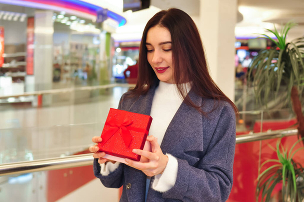 Młoda brunetka z prezentami i torbami na zakupy w centrum handlowym. Wysokiej jakości zdjęcie - Zdjęcie, obraz