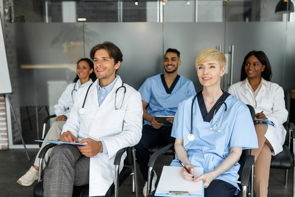 Multiraciální skupina lékařů v pracovních oděvech účastnících se lékařské konference - Fotografie, Obrázek