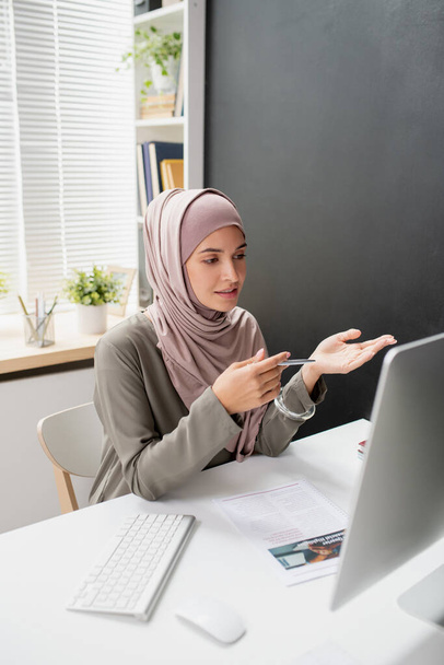 Junge selbstbewusste Lehrerin im Hidschab spricht zu Online-Publikum - Foto, Bild