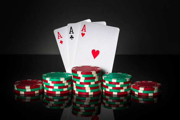 Игра в покер с тремя видами или набором комбинаций. Чипсы и карты на черном столе. Успех и выиграть три туза - Фото, изображение