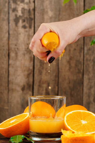 Woman hand squeezes orange juice close up - Foto, Imagem