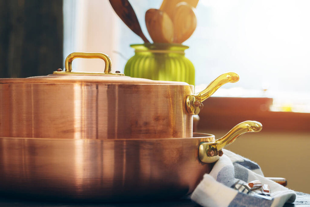 Copper cookware with wooden kitchen utensils close up - Fotó, kép