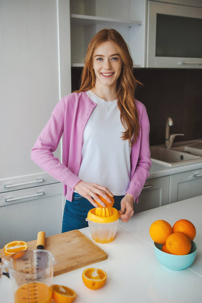 Женщина с рыжими волосами и веснушчатым лицом делает сок на кухне. Здоровое питание - Фото, изображение