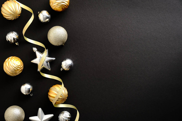 Christmas greeting card template. Christmas golden and silver balls and baubles on dark black background. Flat lay, top view, copy space - Foto, immagini