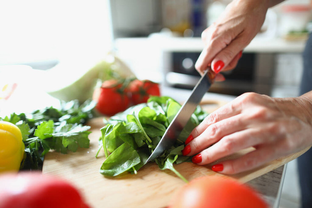 Gros plan d'une femme coupant de la laitue au couteau. Processus de préparation du déjeuner rapide. Légumes frais moelleux sur planche à découper. Concept d'alimentation saine et délicieuse - Photo, image
