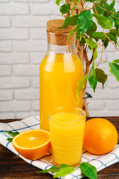 Bottle of fresh orange juice on wooden table against white brick wall background - Φωτογραφία, εικόνα