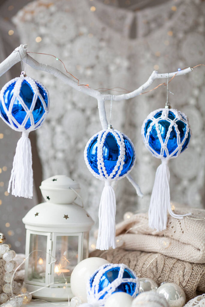 Beautiful New Year's decor using macrame technique. Handmade. Blue balls decorated with macrame hang on a white branch - Photo, image