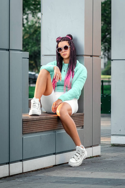 Beautiful, creatively dressed girl with pink pigtails in mint clothes on the background of buildings. The concept of inclusiveness, uniqueness, not like everyone else, non-standard approach - Foto, Imagen